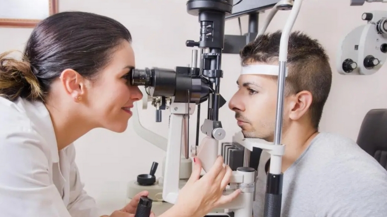 Optometrist examining a red eye for a possible burst blood vessel at a Winnipeg clinic